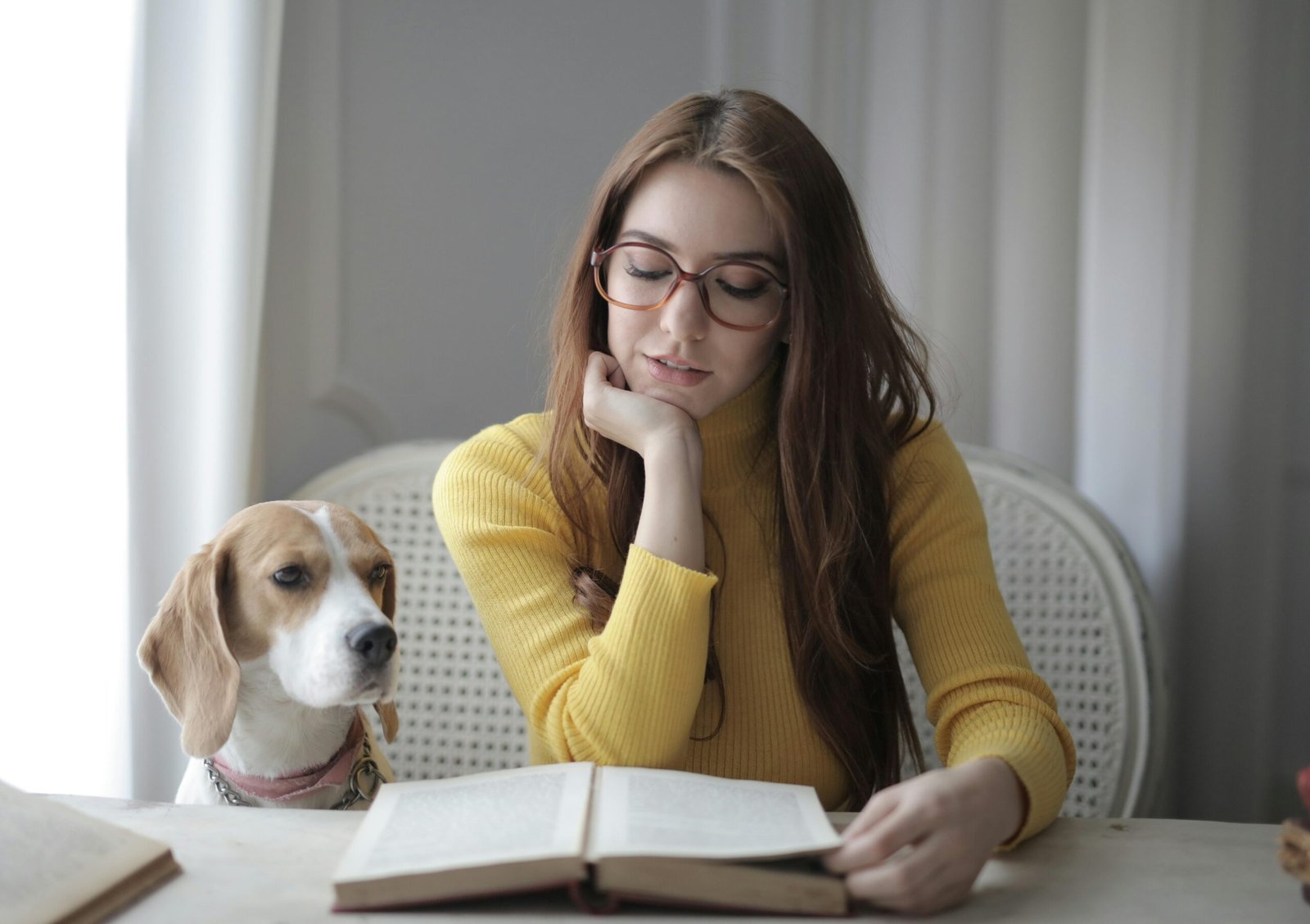 pexels-photo-3786748-3786748 Young woman reading a book with her dog beside her indoors.